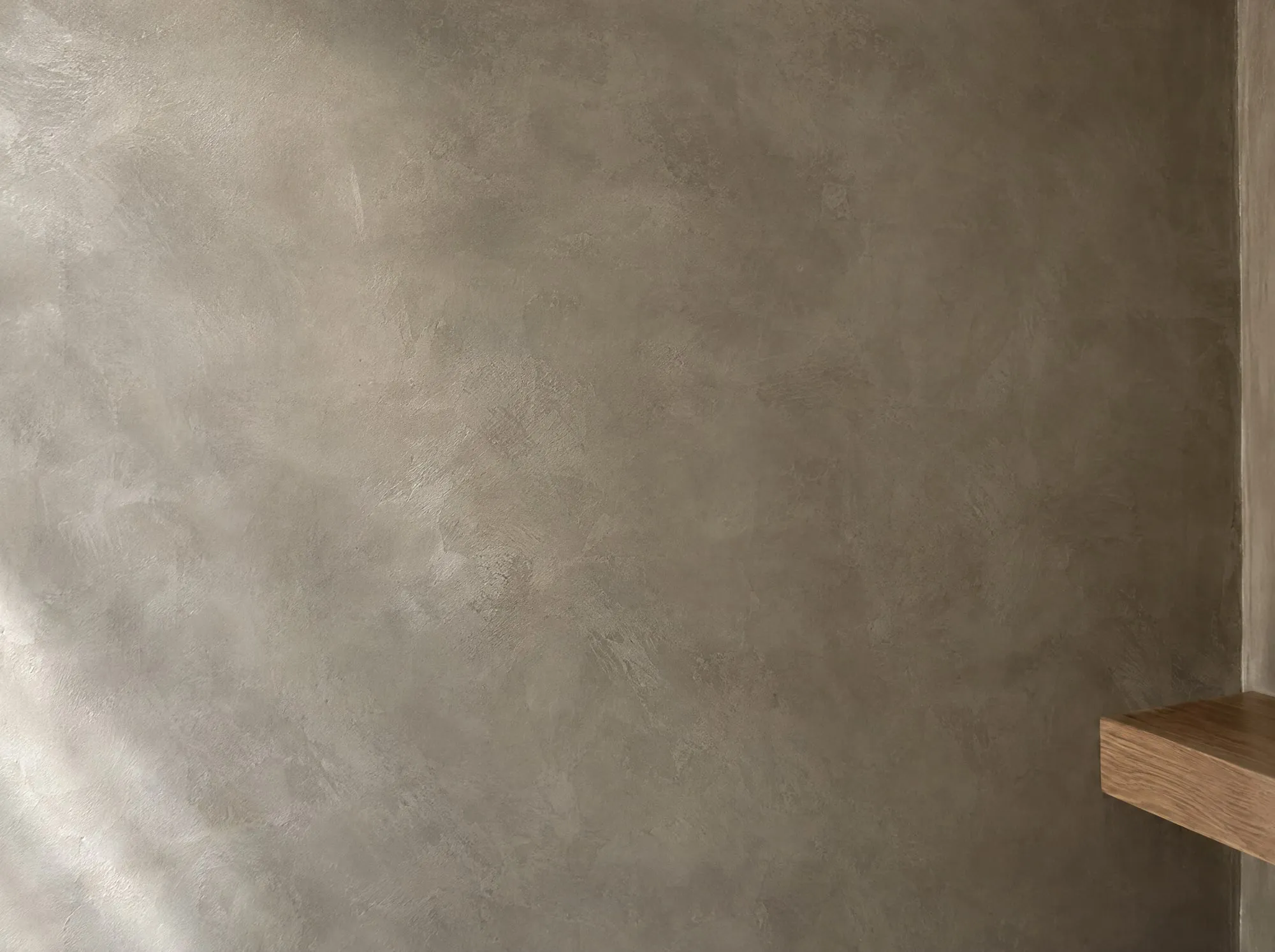 Close-up van een wand in beton ciré met een zachte, gewolkte structuur