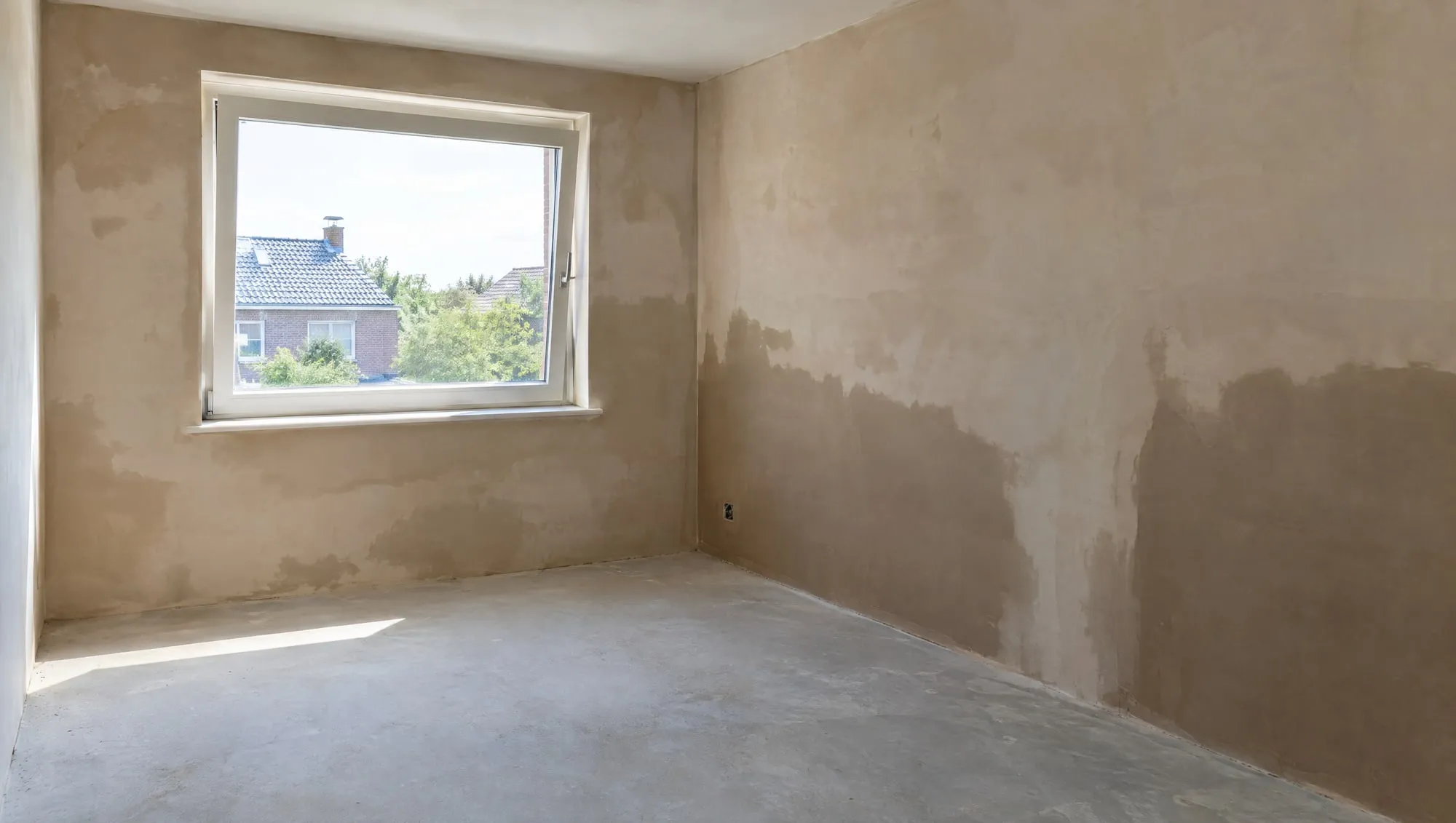 Lege kamer met vers stucwerk dat droogt, raam op een kier